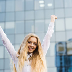 cheerful-woman-raises-hands-up-downtown